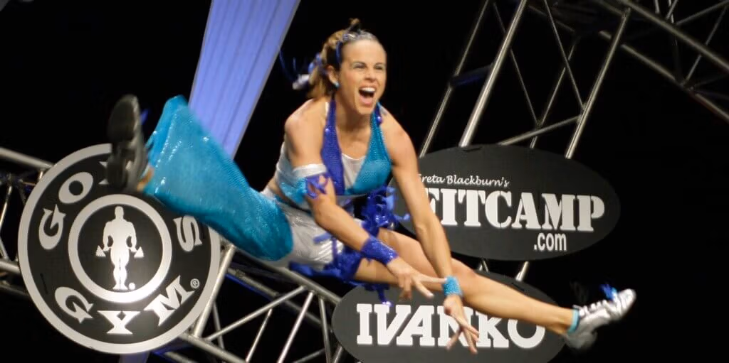 Athelete Amy Bybee caught in image jumping with legs extended and an exhilarated expression on her face.